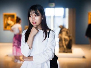 Chinese young woman near picture collection in the museum