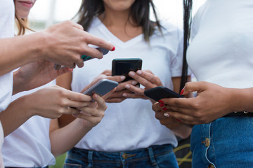 Fototapeta premium Cropped shot of young women using modern phones. Closeup shot of female hands typing on smartphones. Technology concept