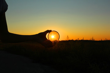 Polarizing filter in hand on sunset background.