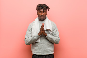 Young fitness african black man holding hands in pray near mouth, feels confident.