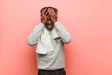 Young fitness african black man covers eyes with hands, smiles broadly waiting for a surprise.