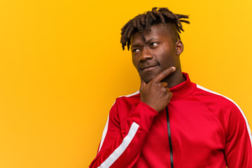 Young fitness african man looking sideways with doubtful and skeptical expression.