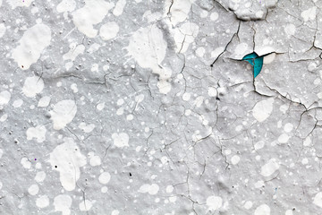 Surface texture with cracks and gray paint and white paint blobs on concrete wall. For abstract backgrounds.