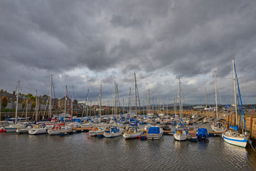 Fototapeta na wymiar The small town of Tayport overlooking its harbour where the Yachts and Motor Boats are moored in the new Marina, with Threatening afternoon clouds coming in.