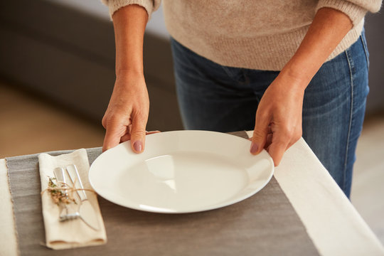 Close-up Of Woman Putting The White Plate On The Table And Serving The Table Before Dinner