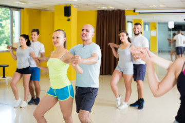 Positive dancing couples learning salsa