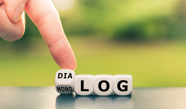 Hand dreht einen W&uuml;rfel und &auml;ndert das Wort "Monolog" in "Dialog".