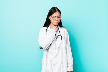 Young chinese doctor woman suffers pain in throat due a virus or infection.