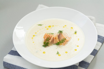 Creamy soup with salmon, potatoes, onions, carrots and green dill in a bowl. A bowl of creamy soup with salmon. Shallow depth, selective focus. 