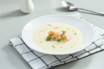 Creamy soup with salmon, potatoes, onions, carrots and green dill in a bowl. A bowl of creamy soup with salmon. Shallow depth, selective focus. 