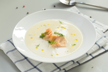 Creamy soup with salmon, potatoes, onions, carrots and green dill in a bowl. A bowl of creamy soup with salmon. Shallow depth, selective focus. 