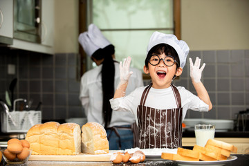 Cute little asian boy a in chef  hats smiling while preparing for baking the dough  in kitchen room at home,family healthy lifestyle concept