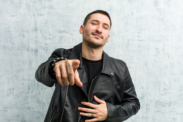 Young rocker man points with thumb finger away, laughing and carefree.