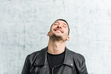 Young rocker man relaxed and happy laughing, neck stretched showing teeth.