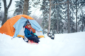 Solo indian man traveller camping through an evergreen winter forest in Canada