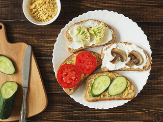 Sandwiches with vegetables and fruits in a white plate on a wooden background . Vegan. Healthy diet. Copy space.