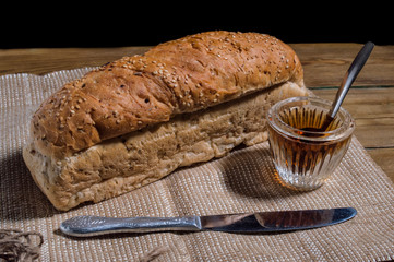sliced bread, glass of honey and  knife on the burlap napkin. Bakery composition. Top view, black background
