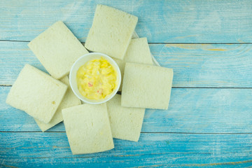 Boiled egg mixed with mayonnaise salad cream in bowl with white bread.