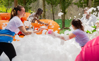Friends picking up balls in inflatable pool with foam