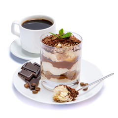 Classic tiramisu dessert in a glass, cup of coffee and pieces of chocolate on white background with clipping path