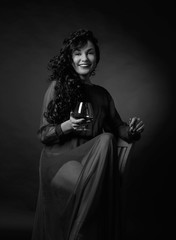 Portrait of attractive brunette in long evening dress with glass of brandy.
