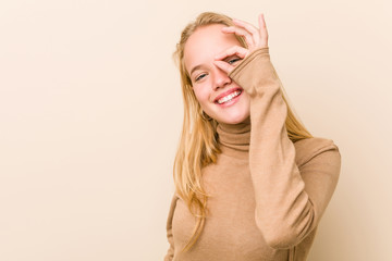 Cute and natural teenager woman excited keeping ok gesture on eye.