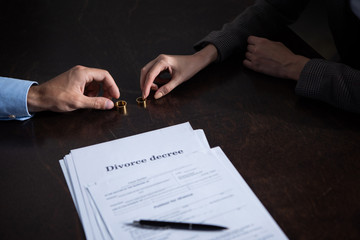Naklejka premium partial view of couple at table with divorce documentsand rings