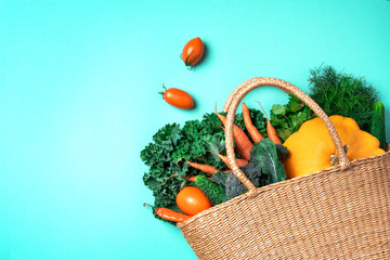 Straw basket with organic vegetables over trendy green background. Healthy food, vegetarian diet....