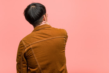 Young chinese man wearing a jacket from behind thinking about something