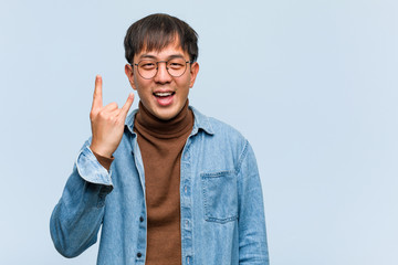 Young chinese man doing a rock gesture