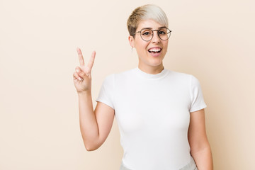 Young authentic natural woman wearing a white shirt showing victory sign and smiling broadly.
