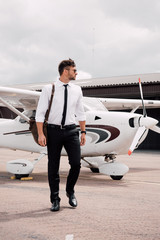 full length view of confident pilot with bag standing near plane under cloudy sky © LIGHTFIELD STUDIOS