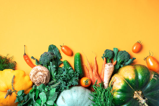 Autumn vegetables on trendy yellow background. Top view. Vegan and vegetarian diet, harvest concept. Ingredients for cooking - pumpkin, tomatoes, cucumber, pepper, kale, broccoli, celery