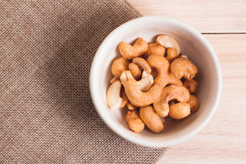 Snack on the table salted Cashew Nuts in the bowl put on sack and wood background with woodden spoon 