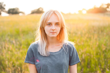 Portrait of beautiful blonde young woman on the field at evening