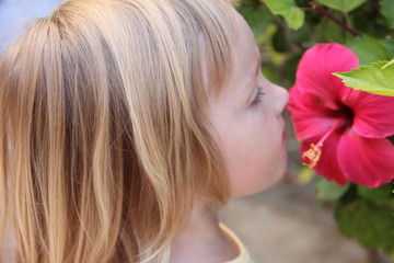 ittle girl sniffing a flower
