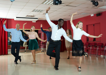 Young people practicing twist movements together at modern dance studio