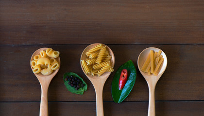Various pasta on a spoon on the wooden floor Top view with copy space
