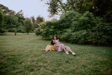 Attractive two ladies in the park enjoying the time together sitting down on the grass and chatting...