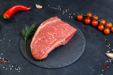 Raw fresh marbled meat and seasonings on dark background top view