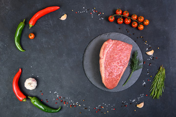 Raw fresh marbled meat and seasonings on dark background top view