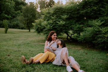 Charismatic and smiling large two pretty ladies falling down on the grass enjoying the time...