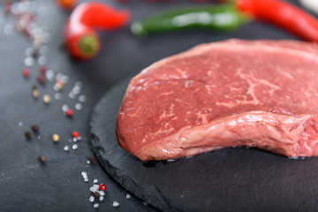 Raw fresh marbled meat and seasonings on dark background