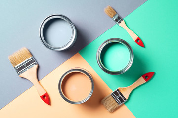 Metal paint cans and paint brushes on multicolor background. Top view. Copy space. Trendy green...