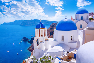 Beautiful Oia town on Santorini island, Greece. Traditional white architecture  and greek orthodox churches with blue domes over the Caldera, Aegean sea. Scenic travel background. - obrazy, fototapety, plakaty