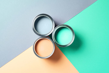 Open cans of paint on bright multicolored background. Top view. Copy space. Trendy green color...