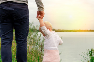 Dad teaches daughter to walk in nature. Father and daughter. First steps.