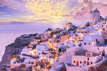 Beautiful view of picturesque Oia village with traditional white architecture  and windmills in Santorini island in Aegean sea at sunset, Greece. Scenic travel background. - obrazy, fototapety, plakaty