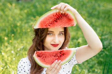 Beautiful young woman is holding two slices of sweet juicy watermelon in front of her face. Girl...