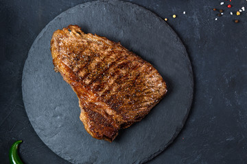 Grilled beef steak ribeye rare on on dark background top view